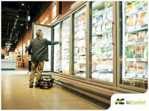 man grabbing food out of refrigerated section at grocery store